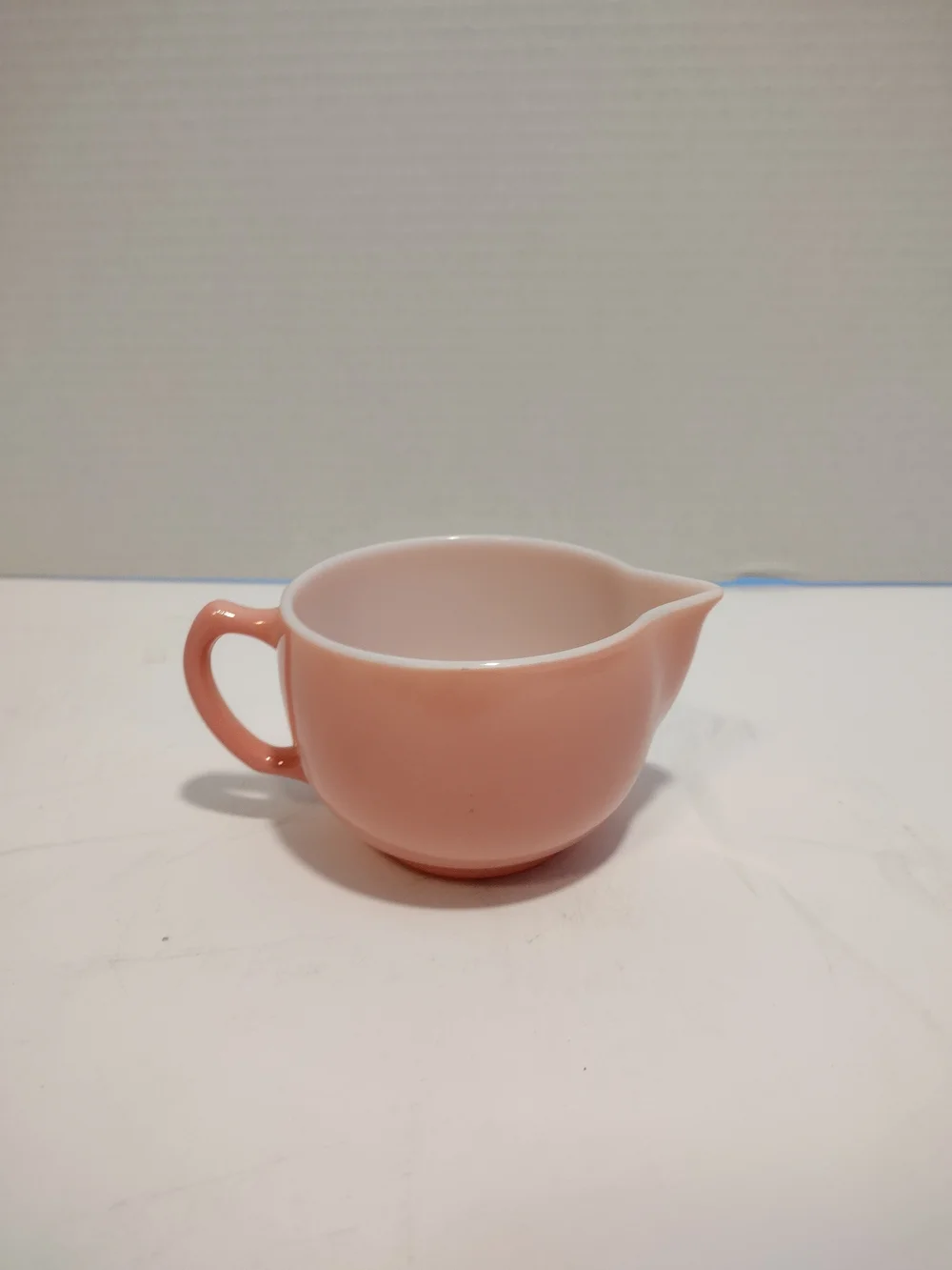 Vintage pink glass creamer by Hazel-Atlas with a C-shaped handle and spout